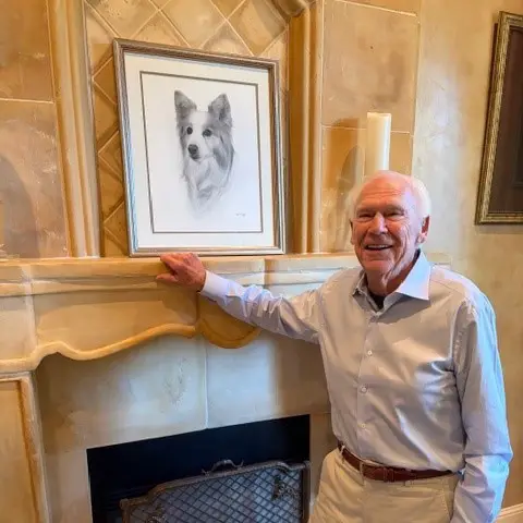 Rich Avanzino by a fireplace with a portrait of his dog, Sido